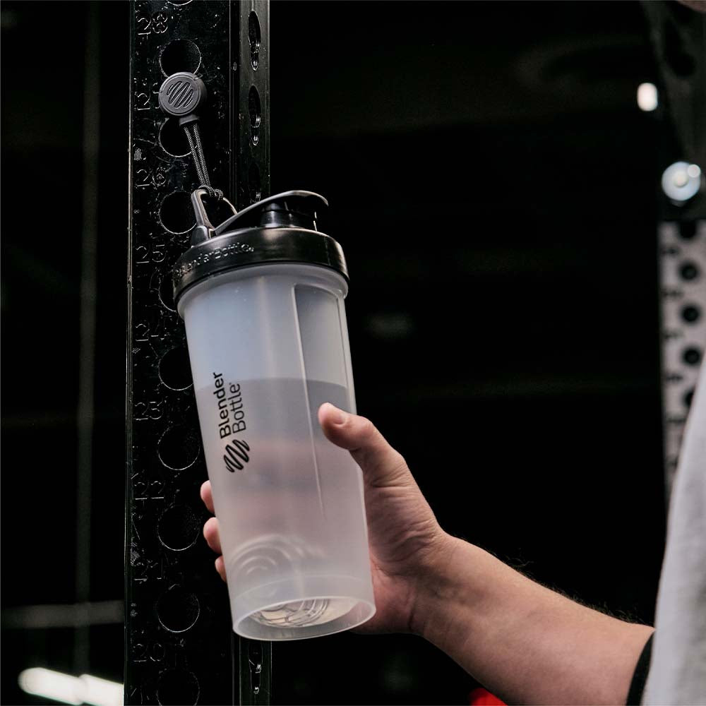 BlenderBottle manget holding shaker bottle to a squat rack. A man is pulling it off.