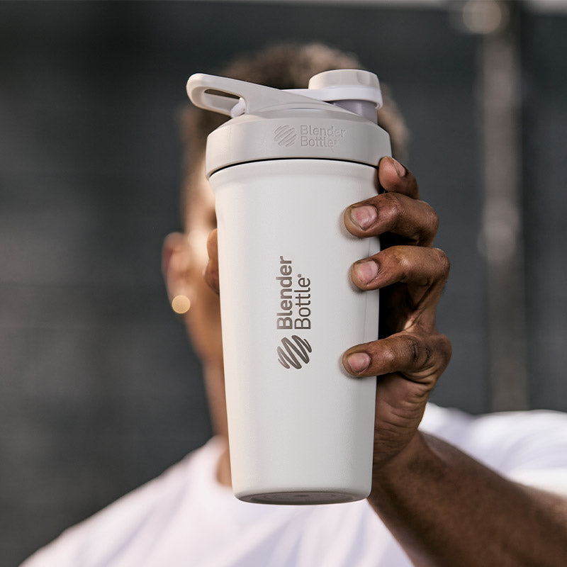Hand holding insulated BlenderBottle shaker cup with twist lid in white