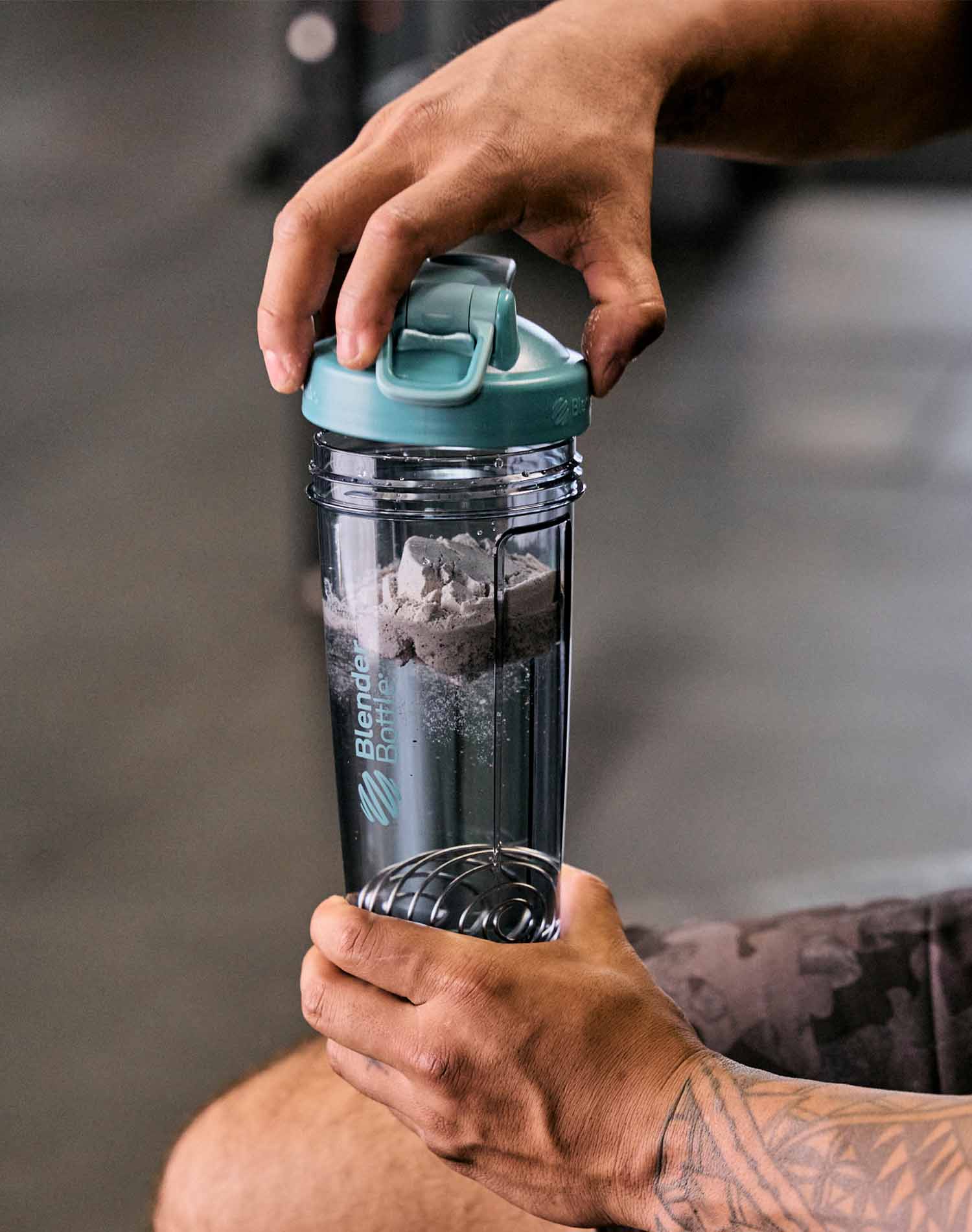 Man placing the lid on a BlenderBottle Pro Series shaker filled with protein powder, liquid, and BlenderBall