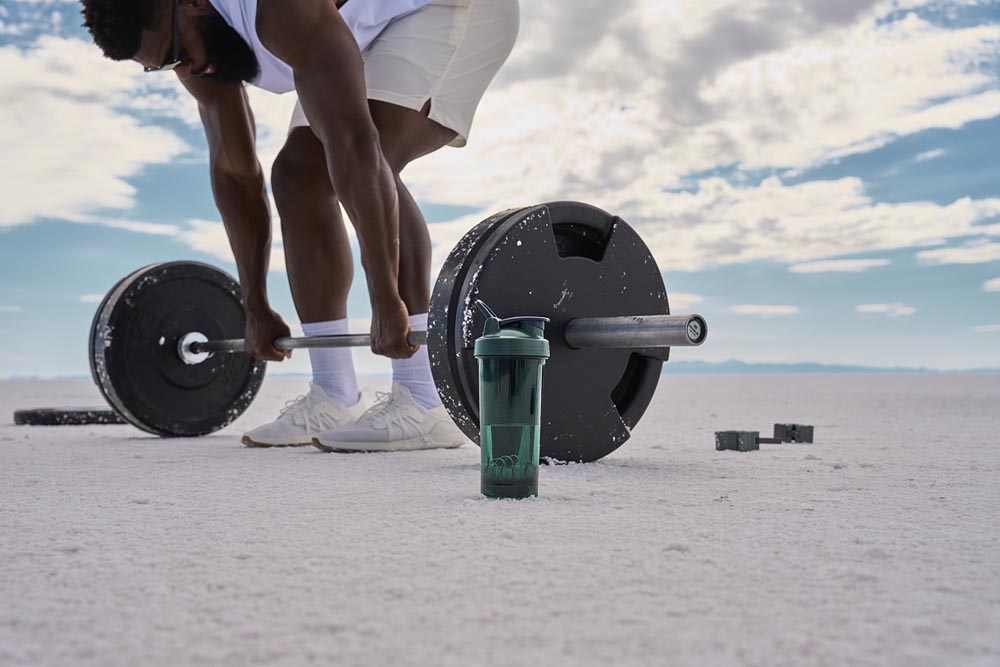 Man lifting next to BlenderBottle ProSeries shaker in dark green.