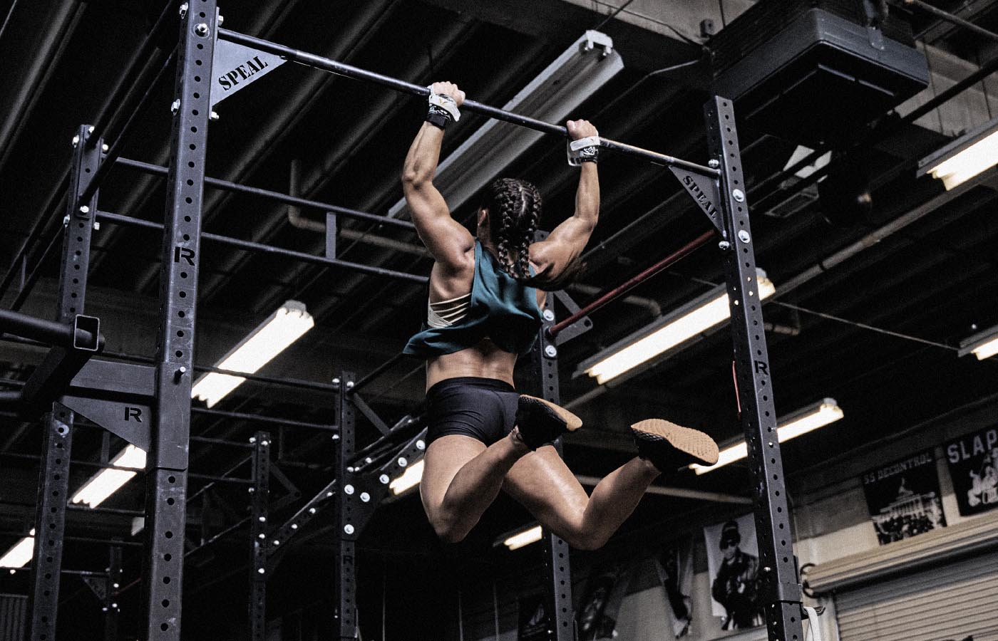 A woman performing a CrossFit workout on a bar, showcasing physical fitness and balance, with focus on her arms and athletic clothing.