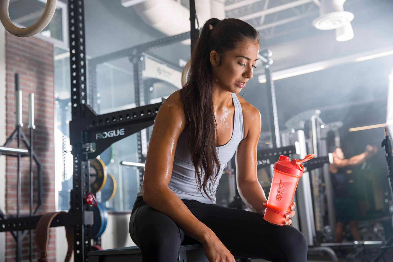 Woman on a workout bench looking at a BlenderBottle