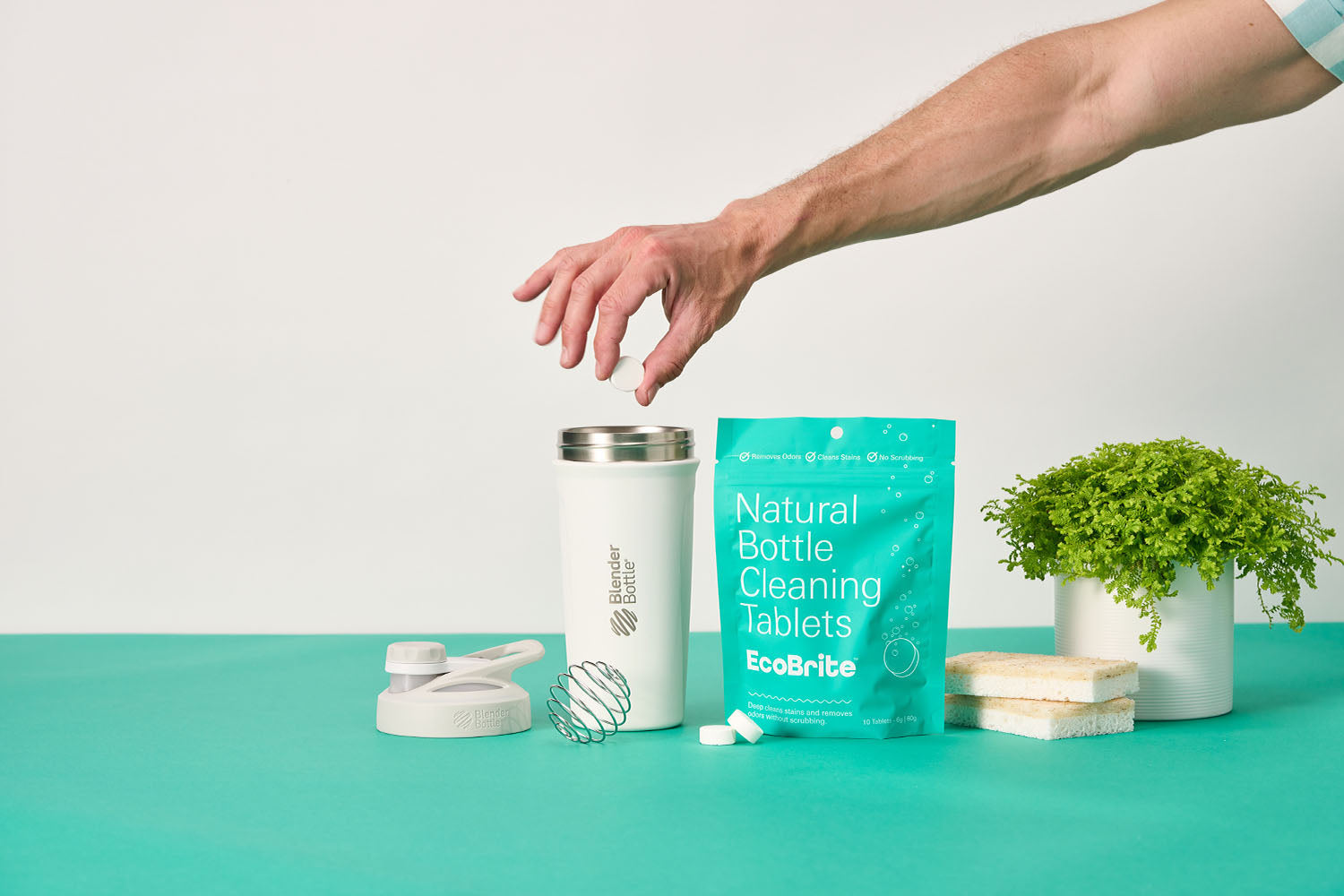 Man dropping an EcoBrite cleaning tablet into a BlenderBottle shaker.