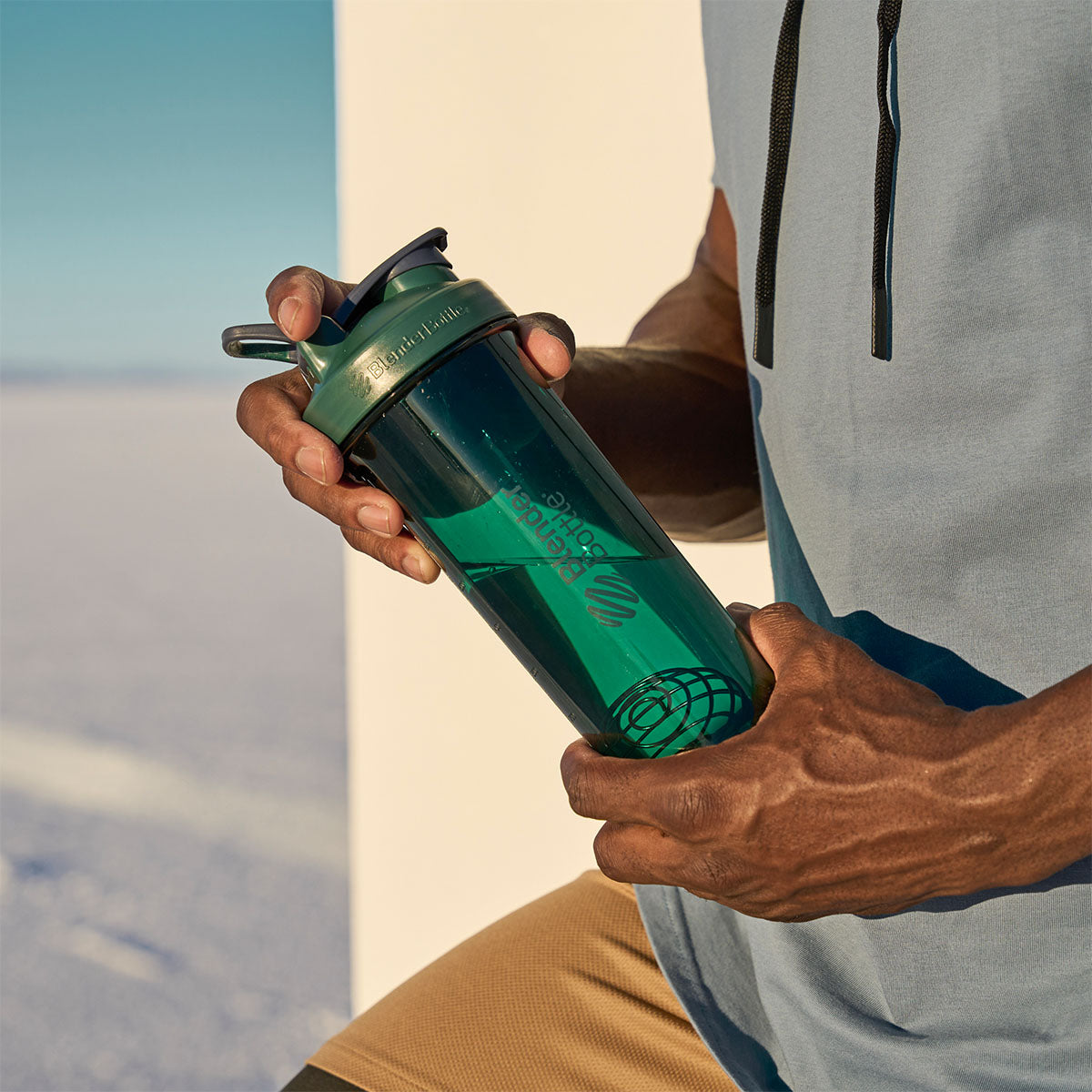 Man holding dark green protein shake cup.