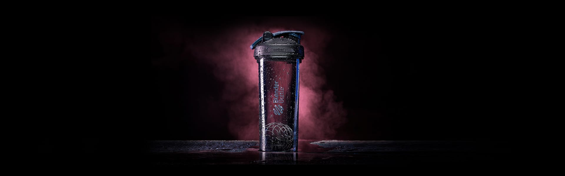 Black Classic BlenderBottle shaker covered in water droplets in front of a red smoke cloud