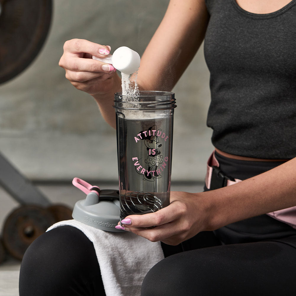 Woman pouring protein powder into a Minnie Mouse shaker bottle