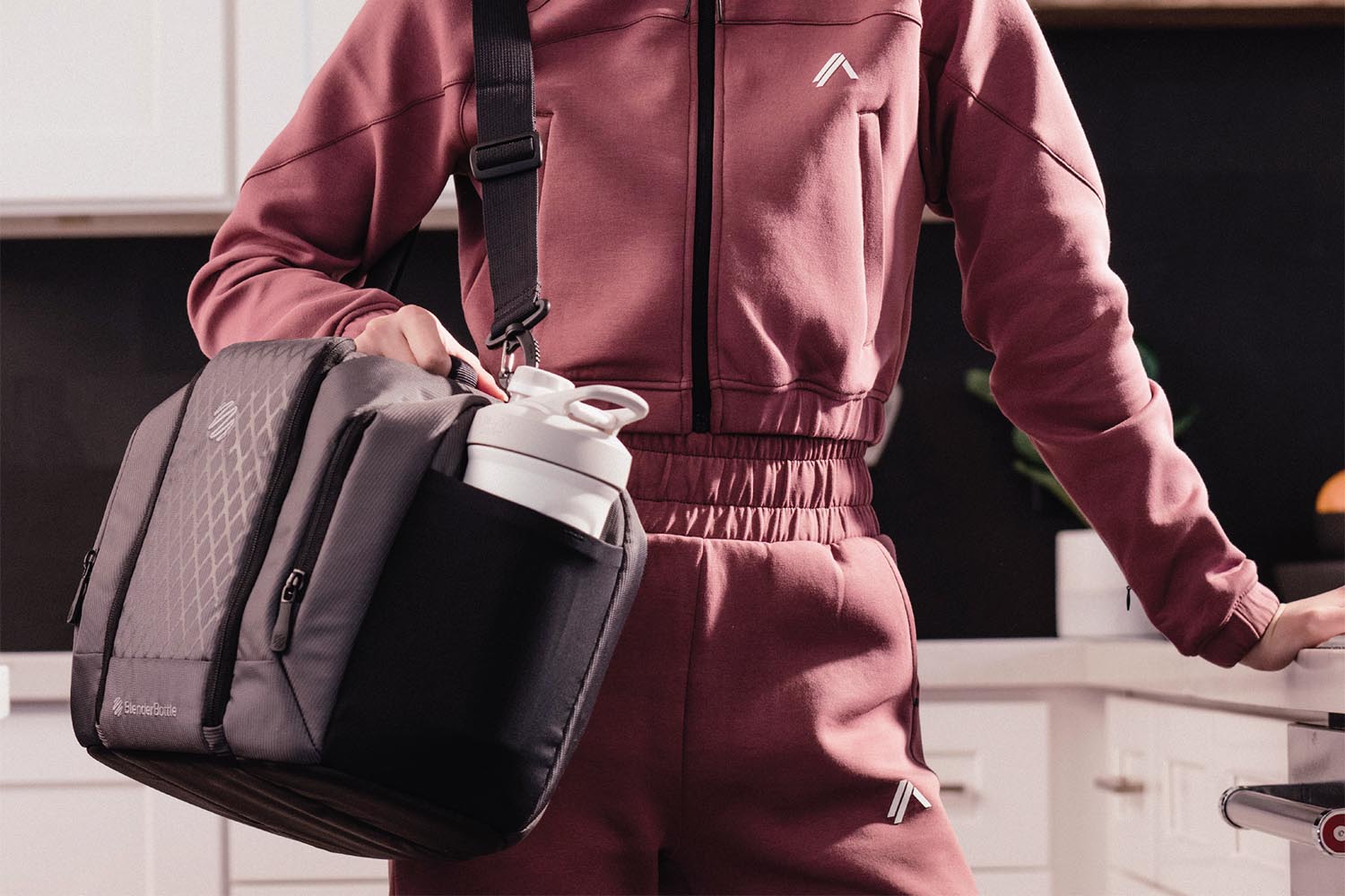 Woman holding a meal prep bag that holds three meals - there is a BlenderBottle in the side pocket
