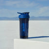 Woman does incline pushup behind blue protien shake cup.